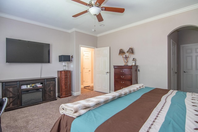 bedroom featuring a ceiling fan, crown molding, arched walkways, baseboards, and carpet