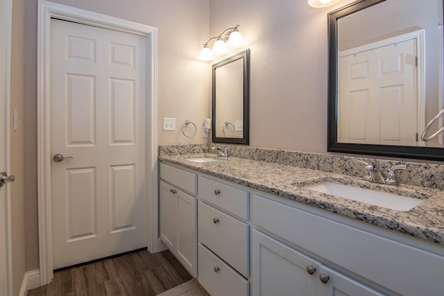 full bath with double vanity, a sink, and wood finished floors