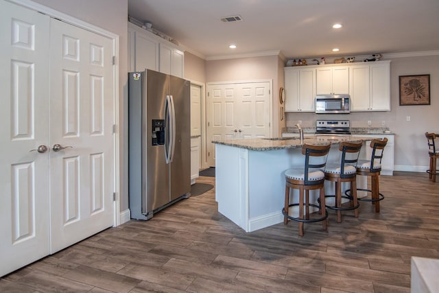 kitchen with light stone countertops, appliances with stainless steel finishes, white cabinetry, baseboards, and ornamental molding
