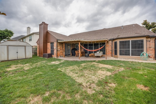 rear view of house with an outbuilding, brick siding, a shed, a yard, and a patio