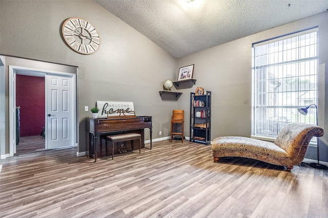 sitting room featuring a textured ceiling, plenty of natural light, light wood-style flooring, and lofted ceiling