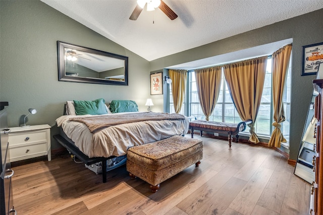 bedroom with a textured ceiling, a textured wall, vaulted ceiling, and wood finished floors
