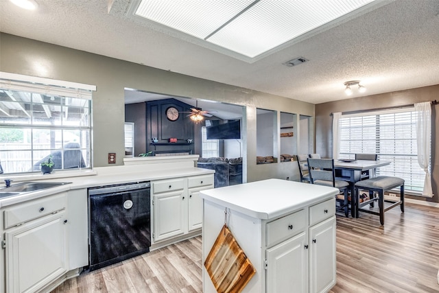 kitchen featuring ceiling fan, a sink, dishwasher, a textured ceiling, and light wood-type flooring