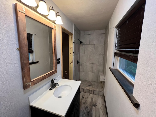 bathroom featuring vanity, wood finished floors, and a tile shower