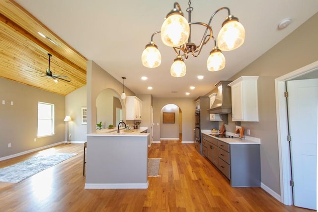 kitchen with light countertops, arched walkways, wall chimney exhaust hood, vaulted ceiling, and black appliances
