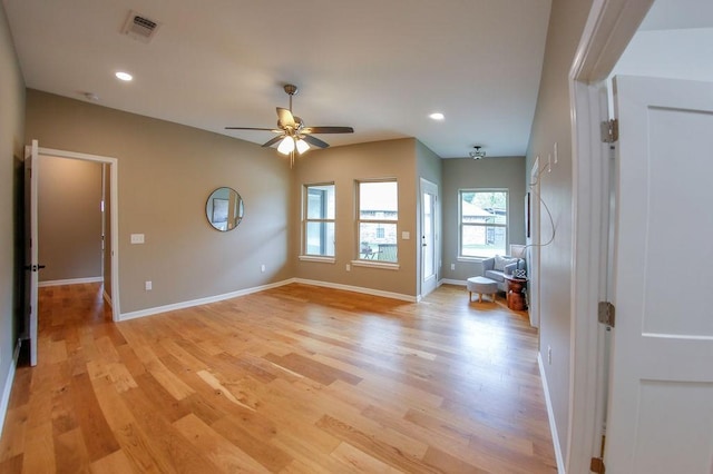 empty room featuring visible vents, ceiling fan, a healthy amount of sunlight, and light wood-type flooring