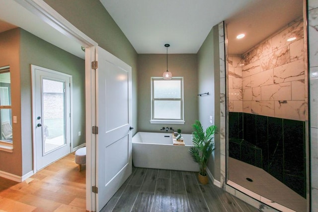 full bathroom featuring baseboards, a walk in shower, a freestanding tub, and wood finished floors