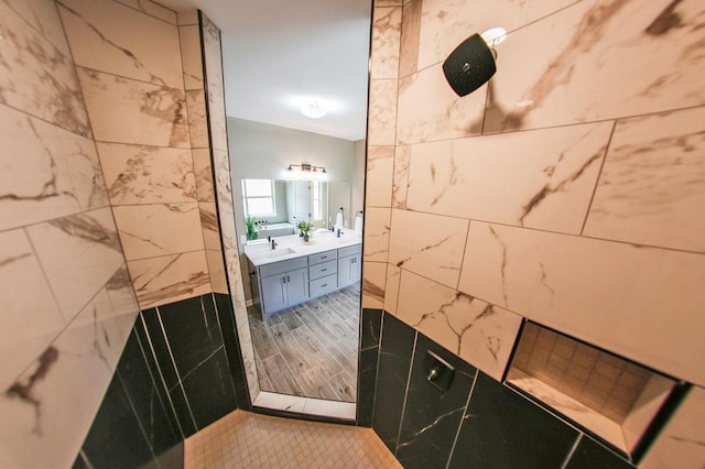 bathroom featuring double vanity and tiled shower