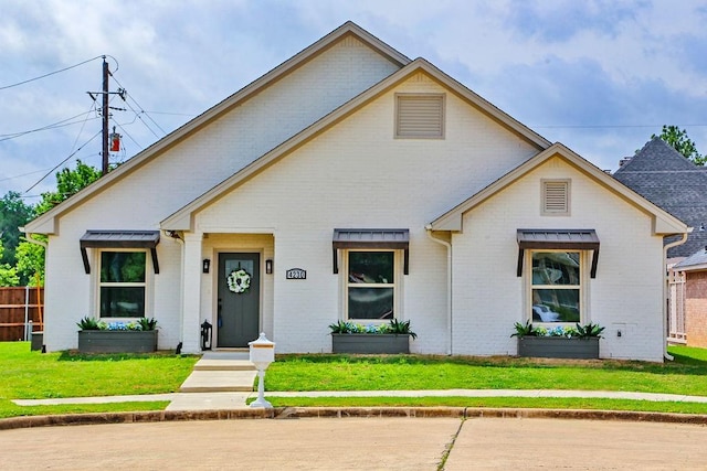 view of front of home featuring brick siding, a front lawn, and fence