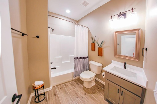 bathroom featuring vanity, toilet, wood finished floors, shower / tub combo, and visible vents