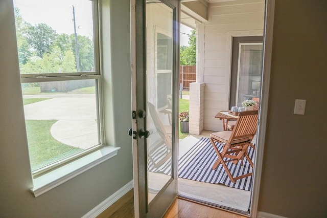 doorway with french doors, baseboards, a wealth of natural light, and wood finished floors