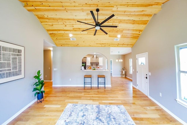 living room with high vaulted ceiling, wood ceiling, ceiling fan with notable chandelier, and wood finished floors