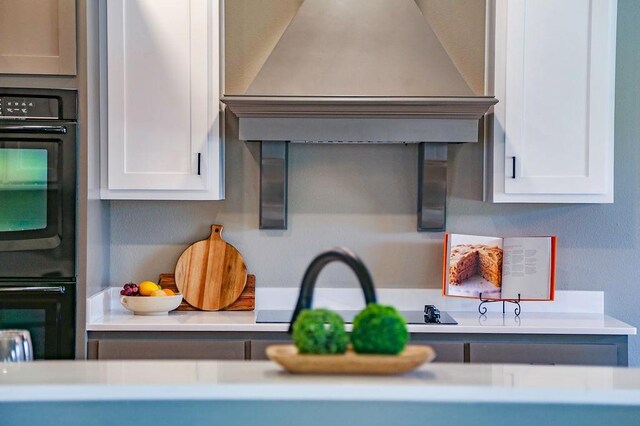 kitchen featuring arched walkways, dobule oven black, a breakfast bar, and custom exhaust hood