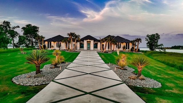 view of front facade featuring a water view, a standing seam roof, metal roof, and a front yard