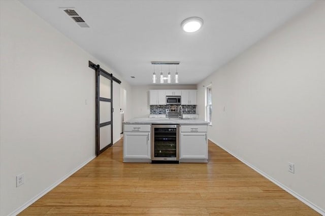 250 Ashland Dr, Woodway, TX 76712 - kitchen featuring visible vents, a barn door, white cabinets, stainless steel microwave, and beverage cooler
