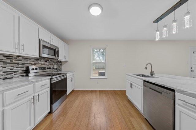 250 Ashland Dr, Woodway, TX 76712 - kitchen featuring baseboards, a sink, white cabinetry, and stainless steel appliances