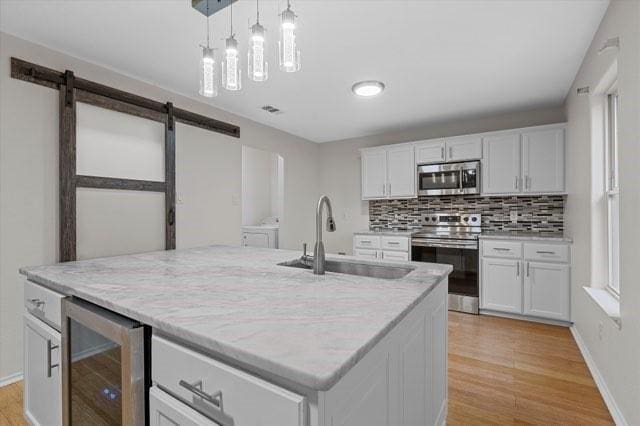 250 Ashland Dr, Woodway, TX 76712 - kitchen with a barn door, a sink, wine cooler, stainless steel appliances, and light wood-style flooring