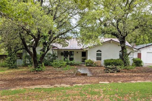 ranch-style home with brick siding, a standing seam roof, metal roof, and a garage
