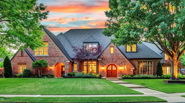 tudor-style house with brick siding and a front yard