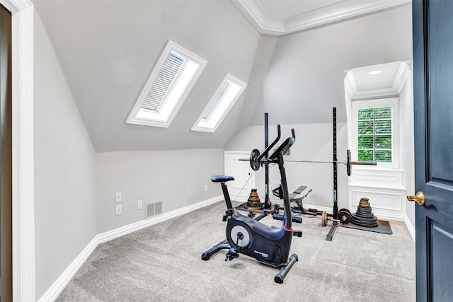 exercise room featuring crown molding, vaulted ceiling with skylight, carpet, baseboards, and visible vents