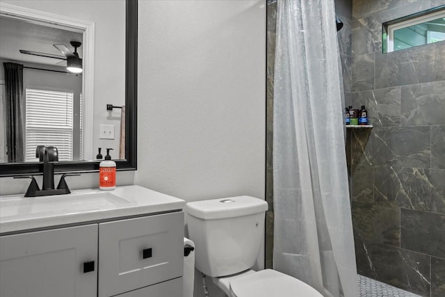bathroom featuring vanity, ceiling fan, a tile shower, and toilet