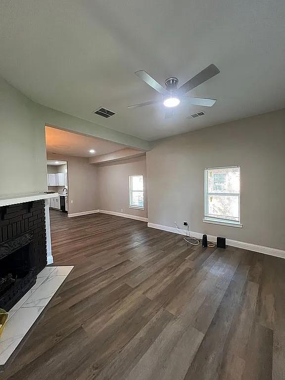 1633 Stoneman, Dallas, TX 75215 - unfurnished living room with a ceiling fan, baseboards, dark wood finished floors, and a brick fireplace