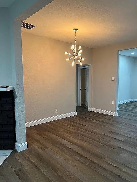 1633 Stoneman, Dallas, TX 75215 - unfurnished dining area with dark wood finished floors, baseboards, and a chandelier