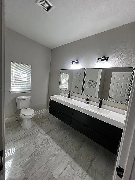 1633 Stoneman, Dallas, TX 75215 - bathroom featuring toilet, marble finish floors, double vanity, baseboards, and a shower