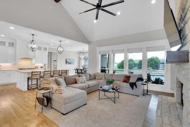 living room featuring high vaulted ceiling, a fireplace, and recessed lighting
