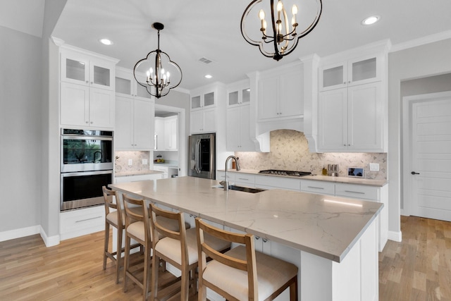 kitchen with a notable chandelier, appliances with stainless steel finishes, a sink, baseboards, and visible vents
