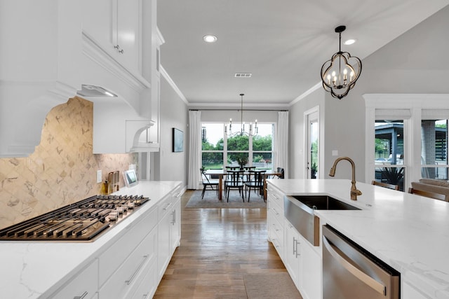 kitchen featuring an inviting chandelier, a sink, stainless steel appliances, backsplash, and visible vents