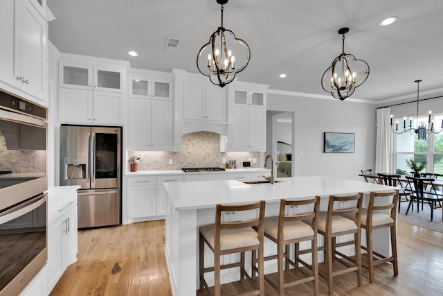 kitchen featuring visible vents, a chandelier, a sink, backsplash, and stainless steel appliances