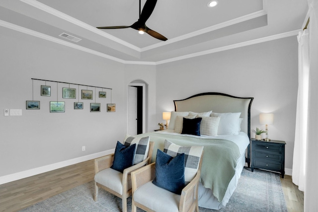 bedroom featuring visible vents, baseboards, a raised ceiling, and wood finished floors