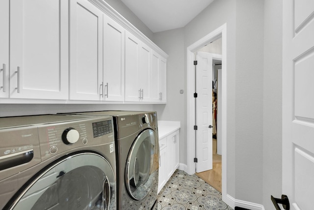 laundry room with separate washer and dryer, cabinet space, and baseboards