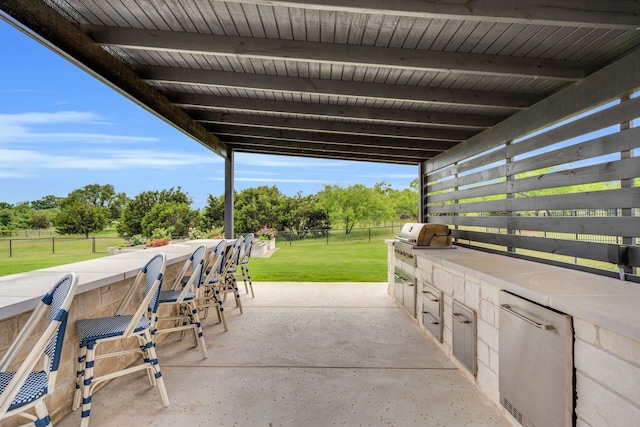 view of patio with exterior bar, fence, exterior kitchen, and area for grilling