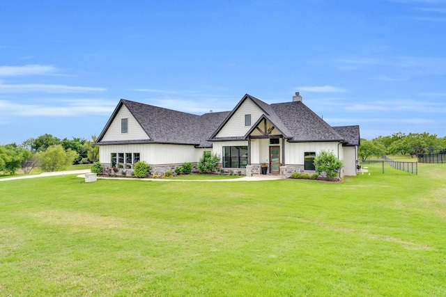 modern farmhouse style home featuring fence, a chimney, a shingled roof, and a front yard
