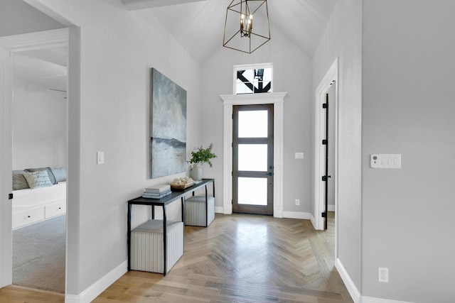 foyer entrance featuring baseboards, lofted ceiling, and a chandelier
