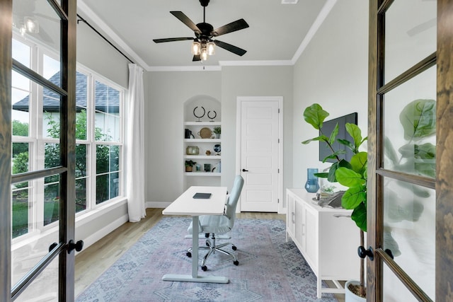 office space with crown molding, baseboards, ceiling fan, and light wood-type flooring