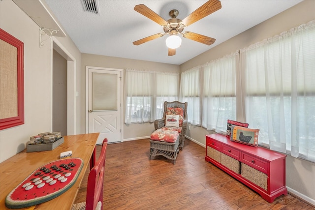 sitting room with a ceiling fan, baseboards, visible vents, and wood finished floors