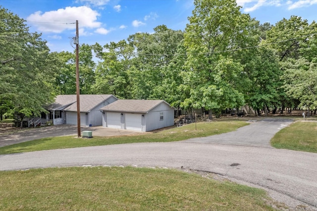 view of front of house featuring a detached garage, driveway, and a front lawn