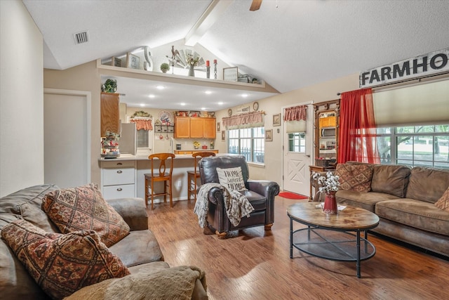 living room featuring ceiling fan, lofted ceiling with beams, wood finished floors, and visible vents