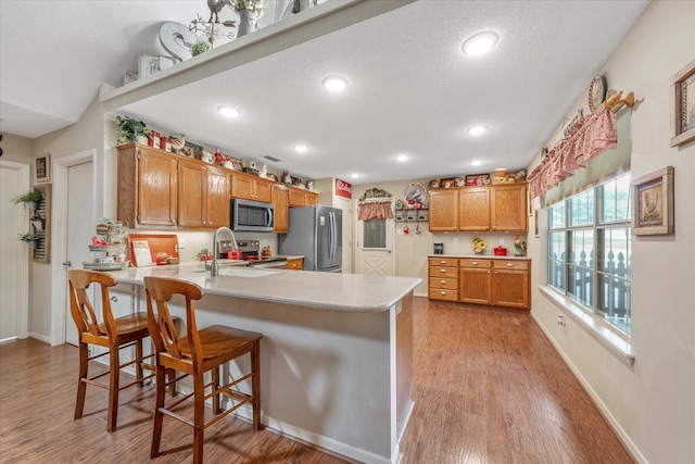 kitchen featuring a peninsula, light countertops, a sink, light wood-style flooring, and stainless steel appliances