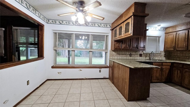 kitchen with a ceiling fan, tasteful backsplash, a sink, light tile patterned floors, and a peninsula