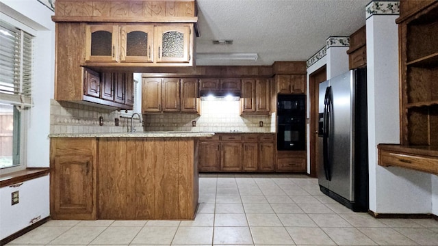 kitchen with light countertops, a peninsula, under cabinet range hood, and black appliances