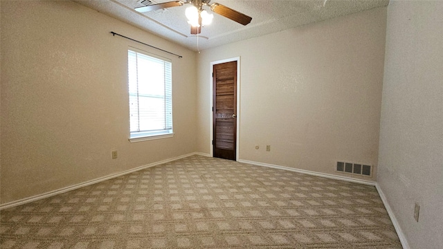empty room featuring carpet floors, baseboards, a ceiling fan, and visible vents