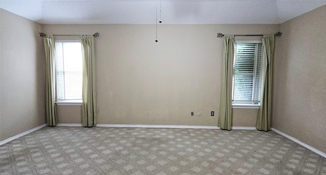 empty room with baseboards, a wealth of natural light, and light carpet