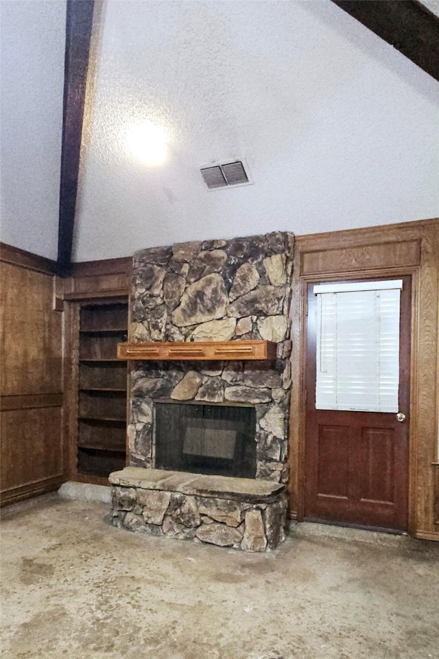 unfurnished living room featuring built in features, vaulted ceiling with beams, wood walls, and visible vents