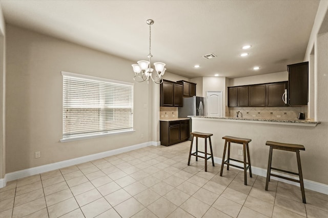 9933 Cottontail Ln, Mckinney, TX 75071 - kitchen featuring decorative backsplash, dark brown cabinets, a chandelier, stainless steel fridge with ice dispenser, and recessed lighting