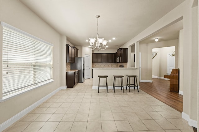 9933 Cottontail Ln, Mckinney, TX 75071 - kitchen featuring a chandelier, dark brown cabinetry, light countertops, a kitchen breakfast bar, and a peninsula