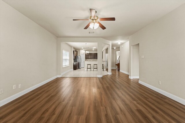 9933 Cottontail Ln, Mckinney, TX 75071 - unfurnished living room with a chandelier, a ceiling fan, wood finished floors, and baseboards